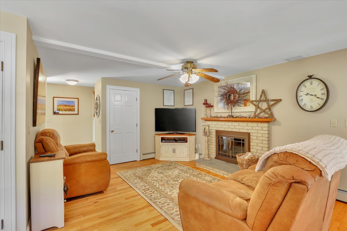 A cozy family room with a brick fireplace, leather furniture, hardwood floors, a large TV, and a rustic star decoration.