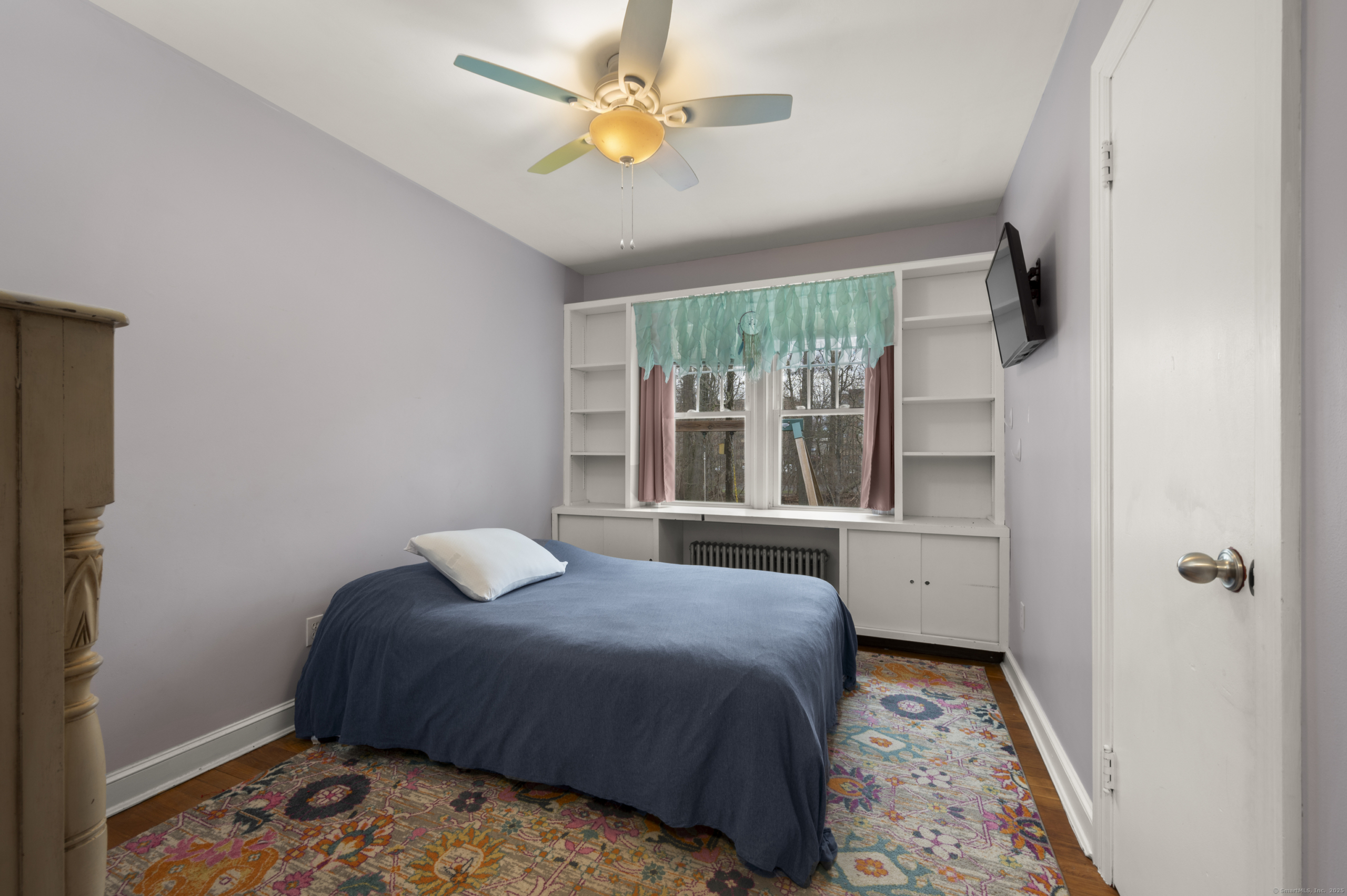 Second bedroom with lavender walls and custom built-in shelving and window seat in Wallingford.