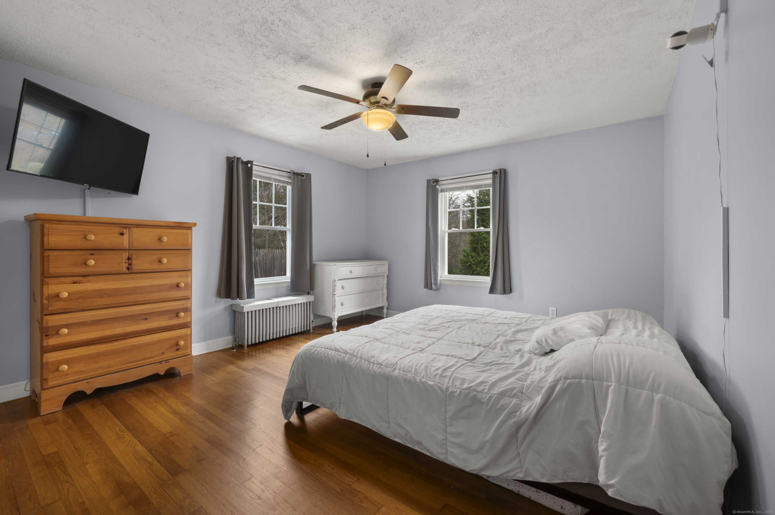 Primary bedroom at 140 Woodhouse Ave with light blue walls, hardwood floors, and natural wood trim.