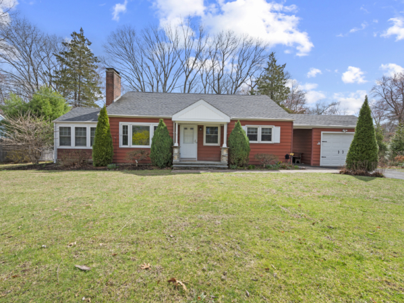Front exterior of 140 Woodhouse Ave, a red ranch-style home with a large lawn and attached garage.