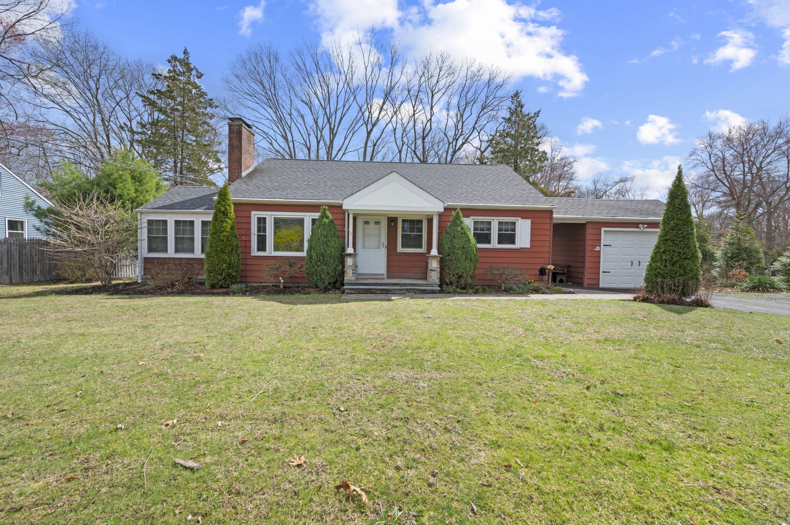 Front exterior of 140 Woodhouse Ave, a red ranch-style home with a large lawn and attached garage.