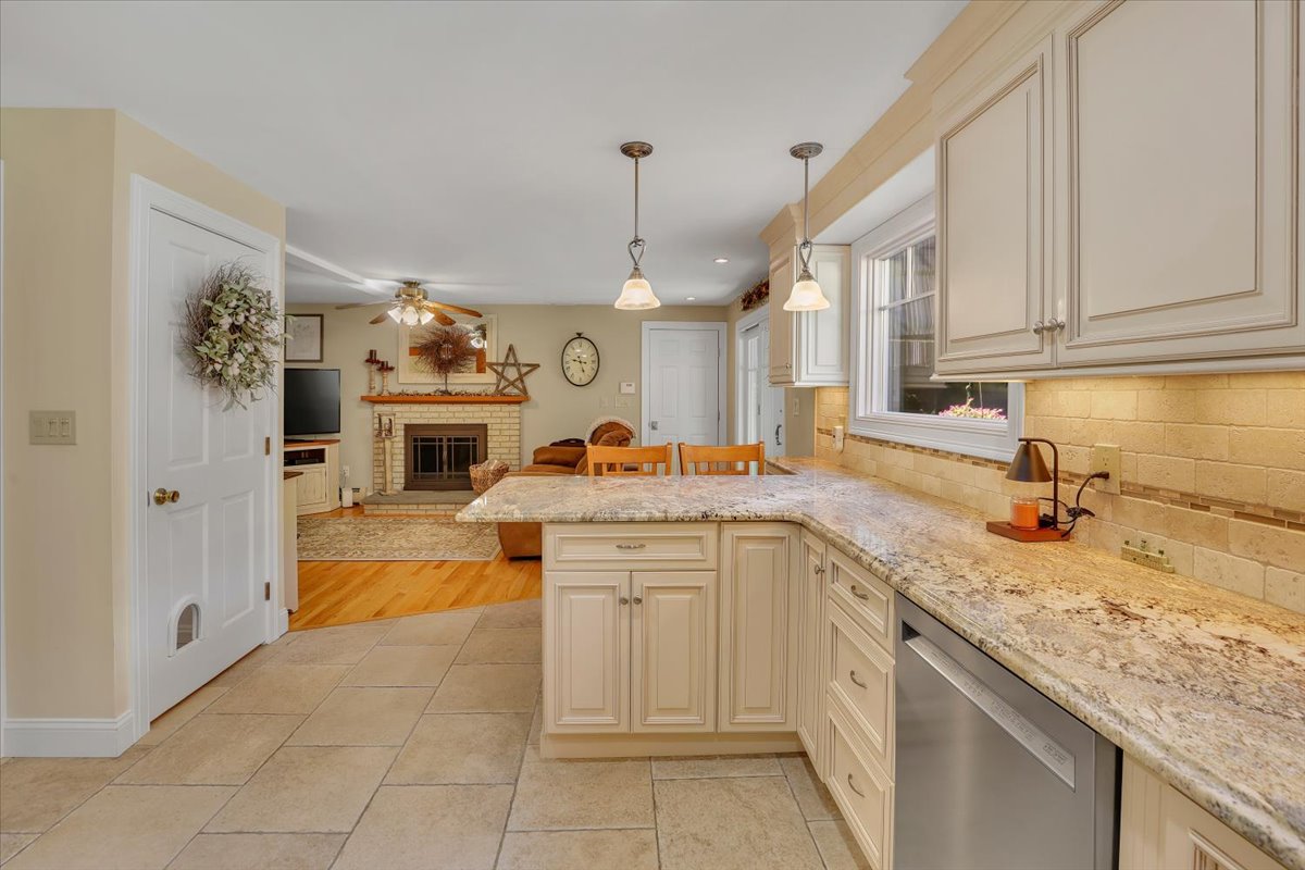 An open-concept view from the kitchen showing a granite countertop peninsula looking through to a living area with a fireplace.