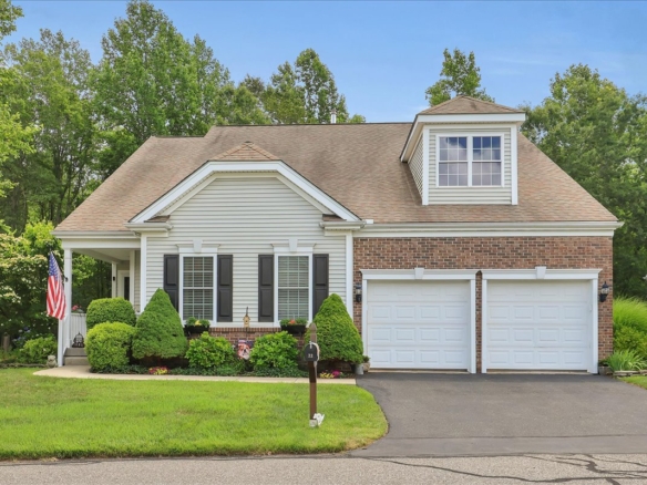 Front exterior of 33 Wadsworth Ln featuring a Cape Cod style home with a brick and vinyl facade, two-car garage, and manicured landscaping.