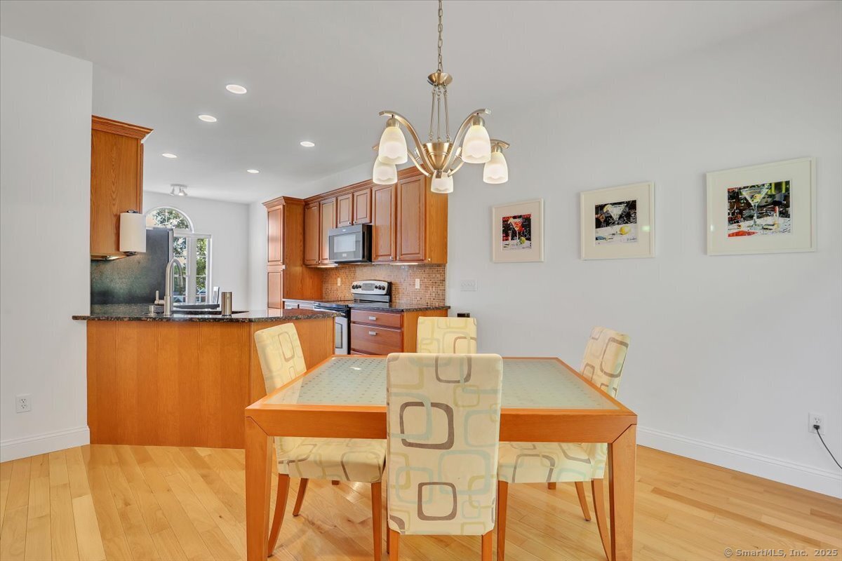 Bright dining area with a modern wooden table, patterned upholstered chairs, a contemporary gold chandelier, and wall art at 5 Sonoma Ln.