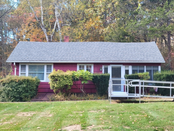 Front view of a red ranch-style home at 60 Chestnut Lane in Hamden, CT, featuring a metal accessibility ramp and lush green lawn.