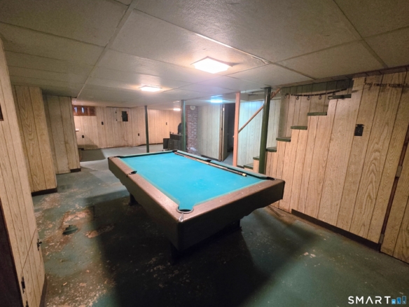 Finished basement recreation room featuring a large pool table and wood paneling.