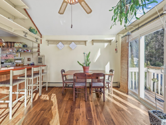 A wooden dining table in a bright room with sliding glass door access to a large wooden deck.