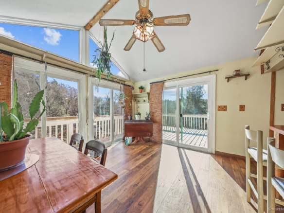 Bright dining area with vaulted ceilings, a ceiling fan, and sliding glass doors leading to an outdoor deck.