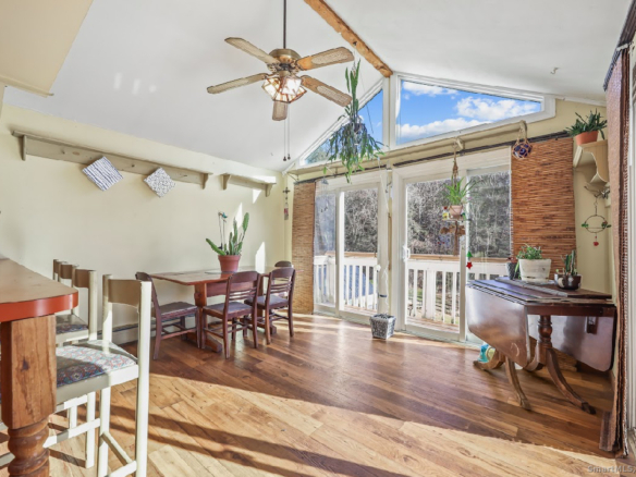 Open concept kitchen and dining area with architectural shelving and a vaulted ceiling in a Thomaston ranch.