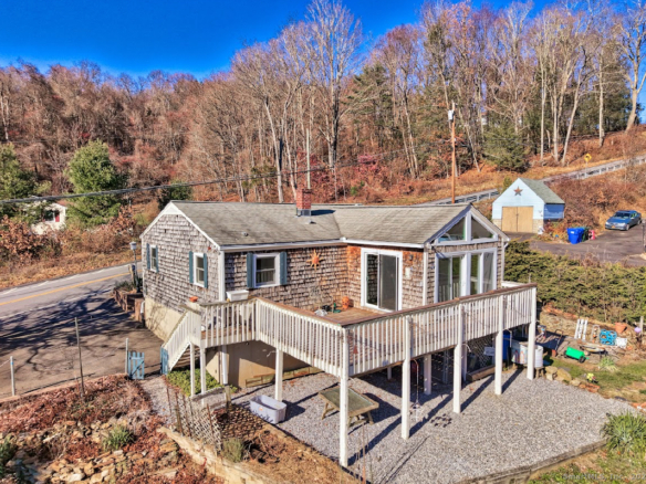 View from the wooden deck at 1101 Hickory Hill Road, Thomaston, looking out toward distant hills and a clear blue sky.