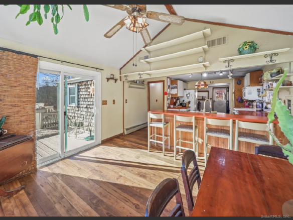 A sun-drenched dining space at 1101 Hickory Hill Road with floor-to-ceiling windows overlooking a wooded backyard.