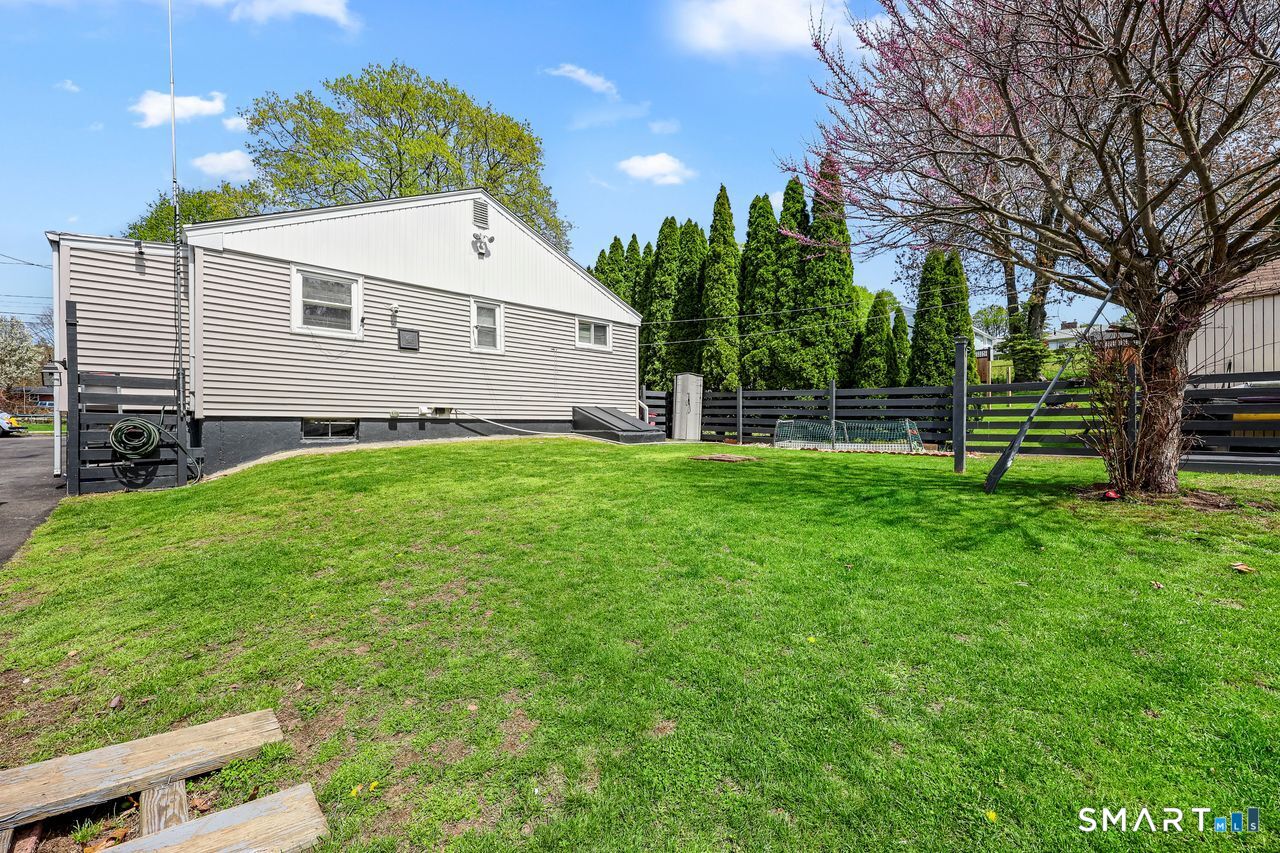 Private fenced-in backyard with lawn and mature trees in Meriden