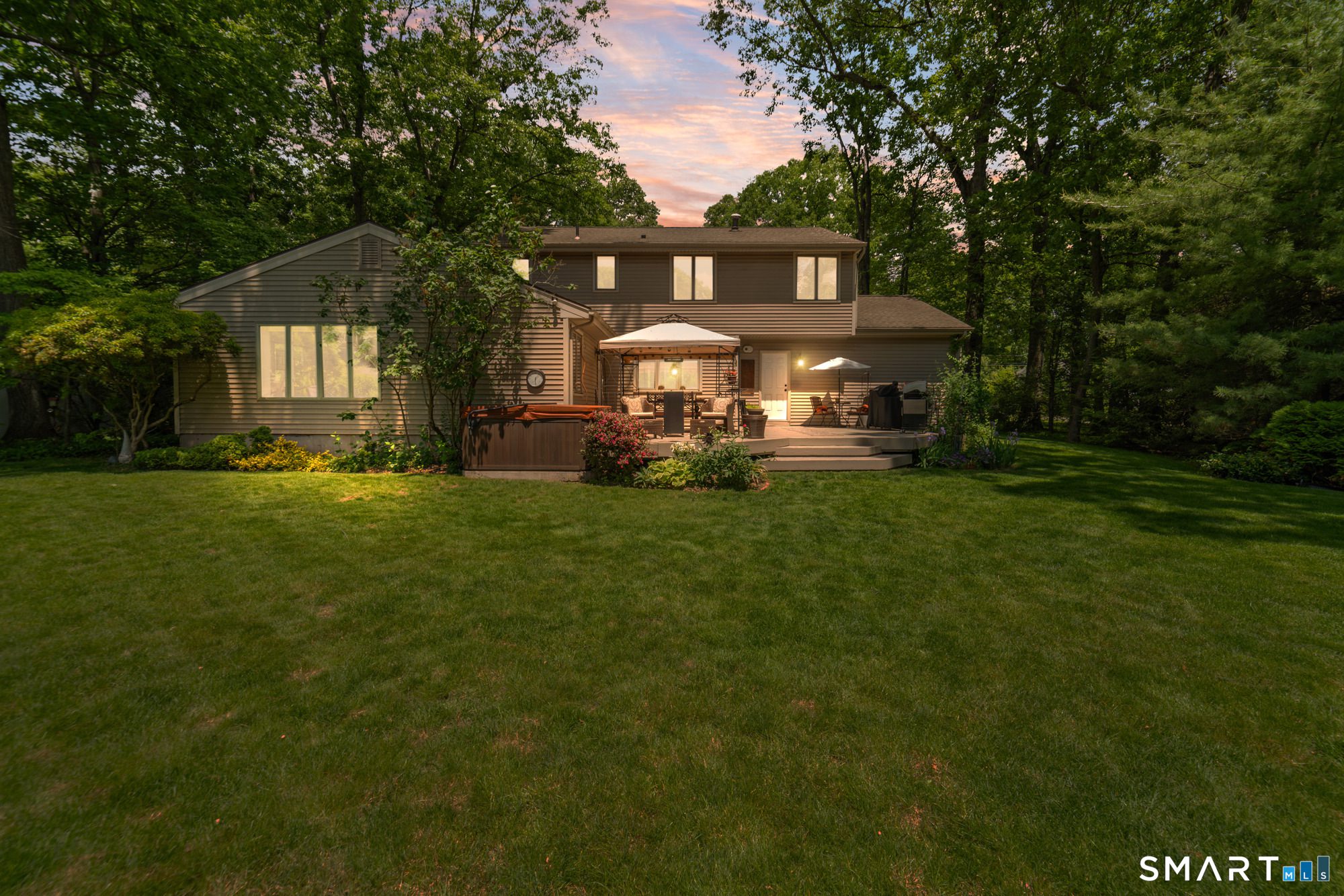 Rear view of a residential property in Cheshire at twilight, featuring a spacious deck and serene backyard setting.