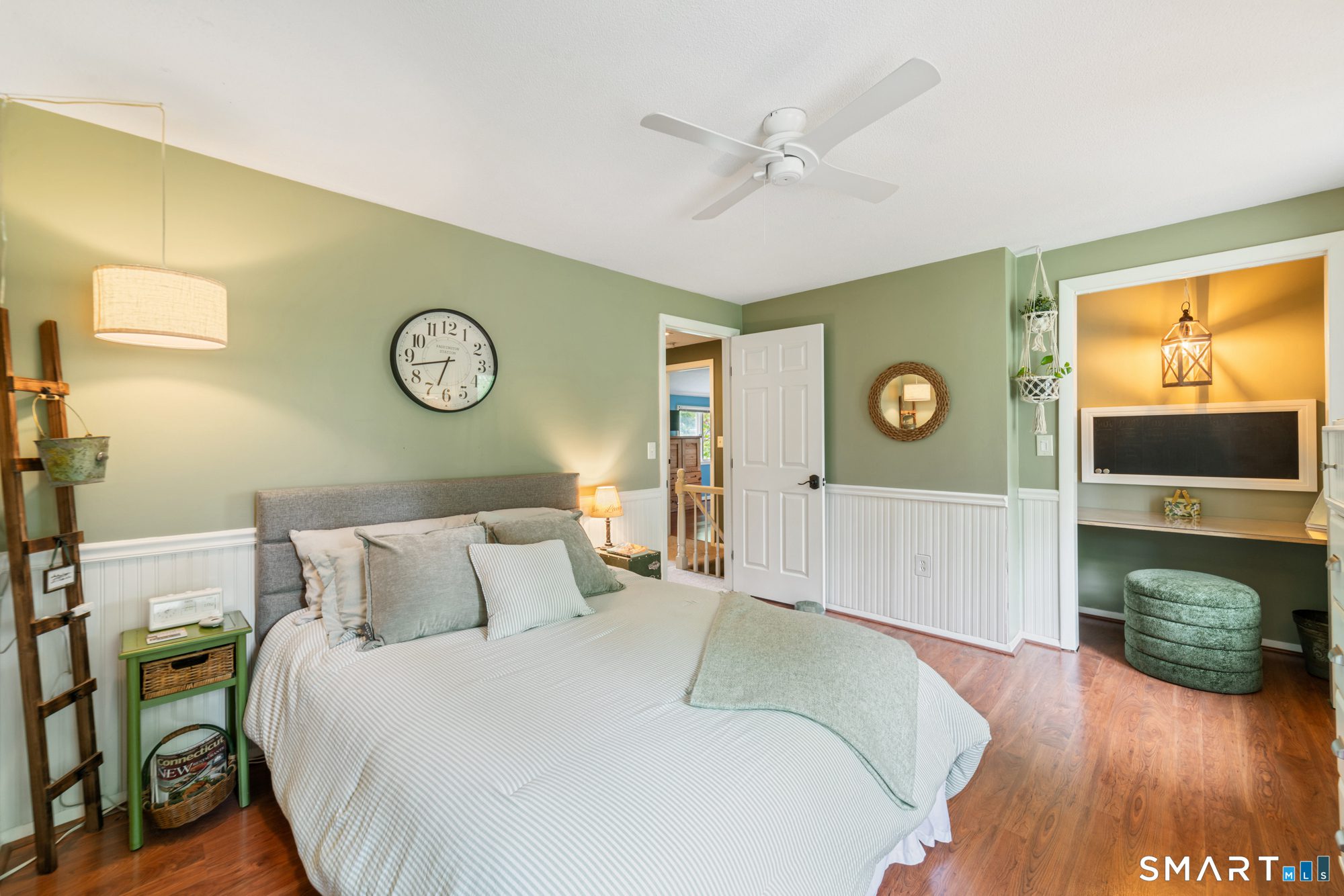 Cozy guest bedroom with soft sage green walls, a comfortable queen bed, and a private built-in desk area.