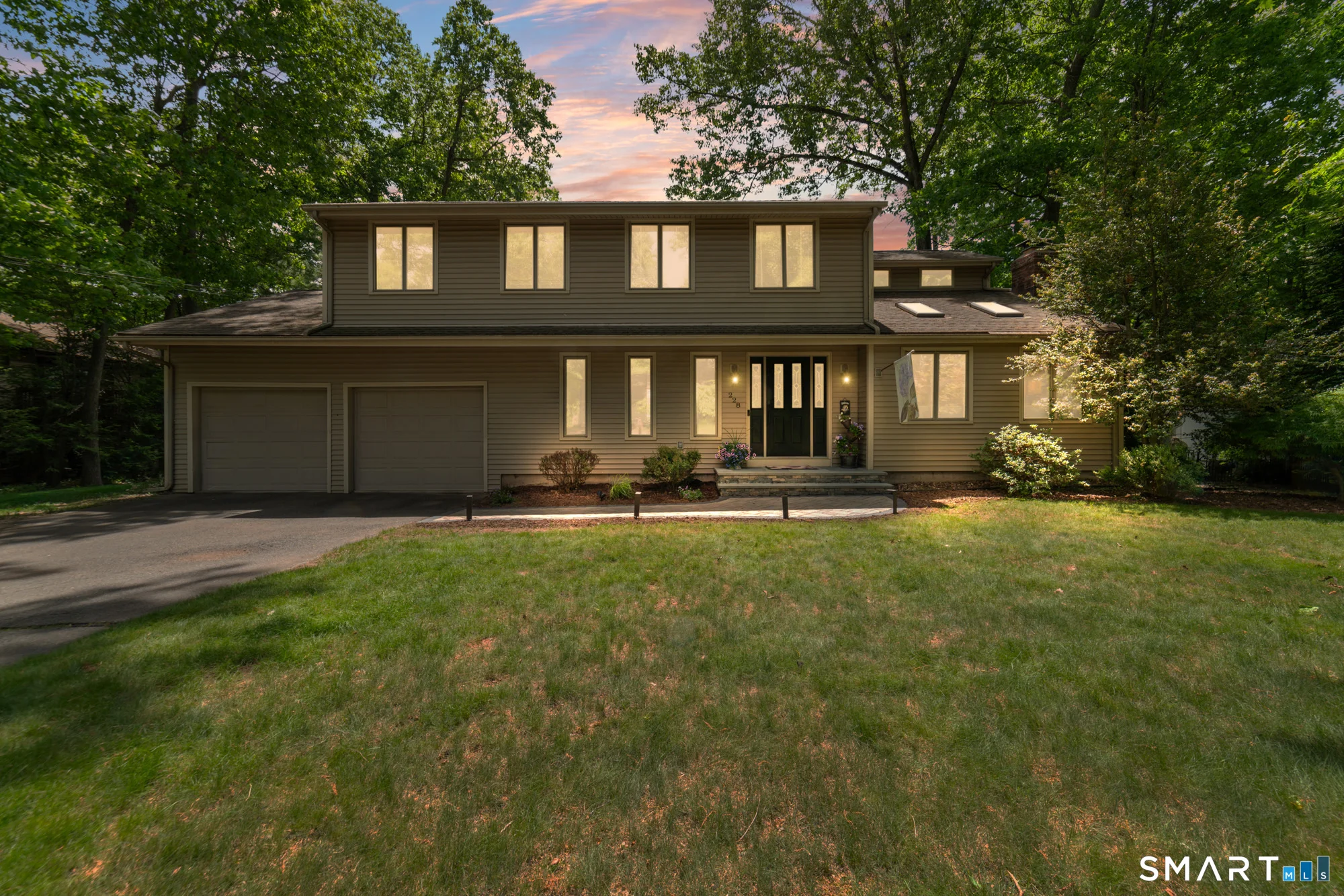 Front exterior view of a beautiful single-family home in Southington, CT, showcasing manicured landscaping and a two-car garage.