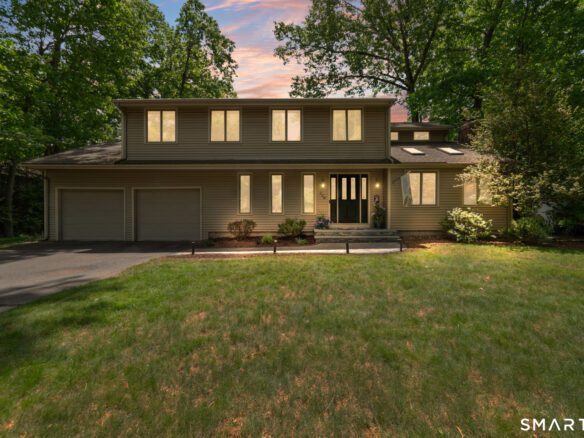 Front exterior view of a beautiful single-family home in Cheshire, CT, showcasing manicured landscaping and a two-car garage.