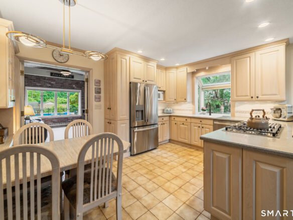 Well-appointed kitchen featuring light wood cabinetry, stainless steel appliances, and an open layout to the dining area.