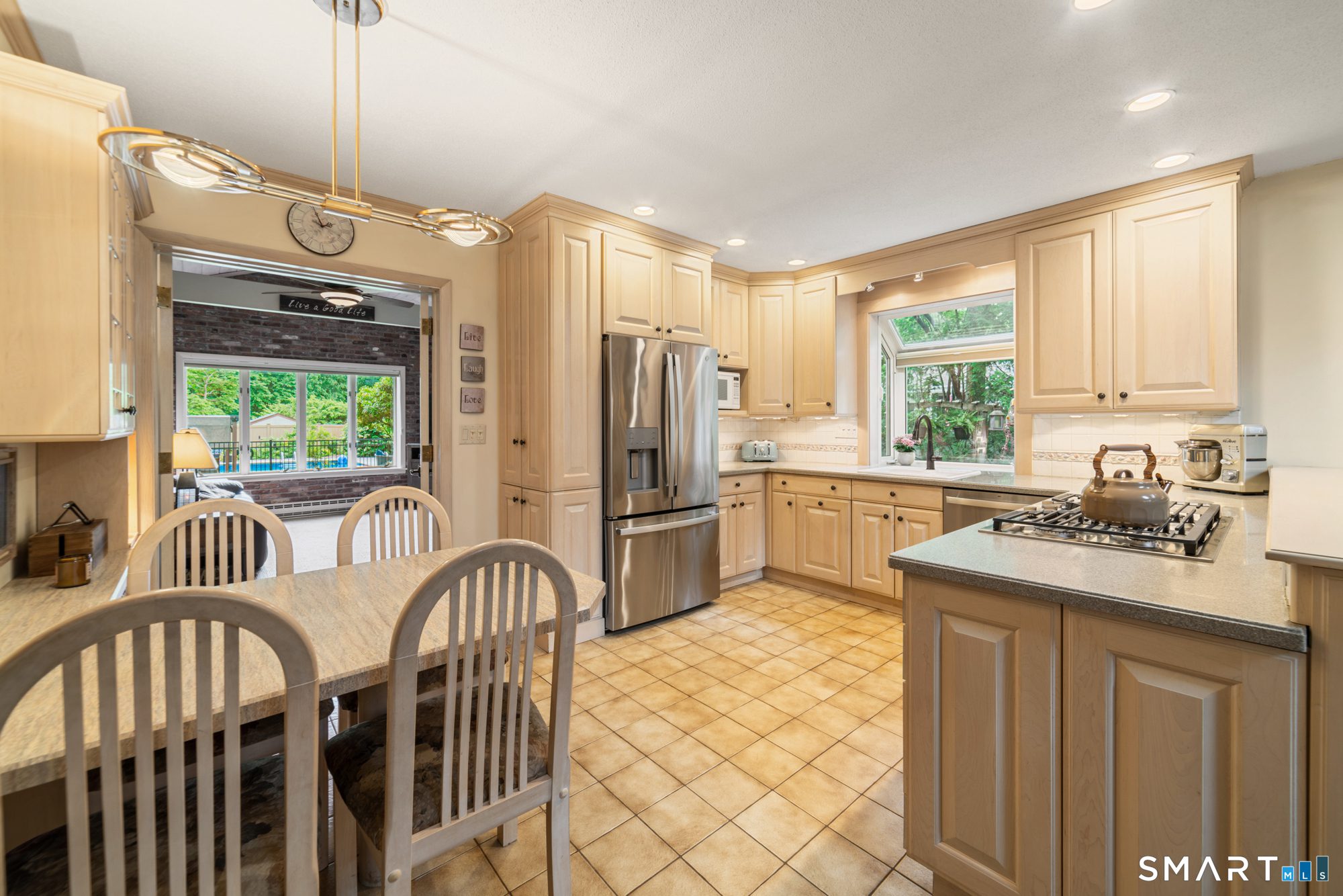 Well-appointed kitchen featuring light wood cabinetry, stainless steel appliances, and an open layout to the dining area.