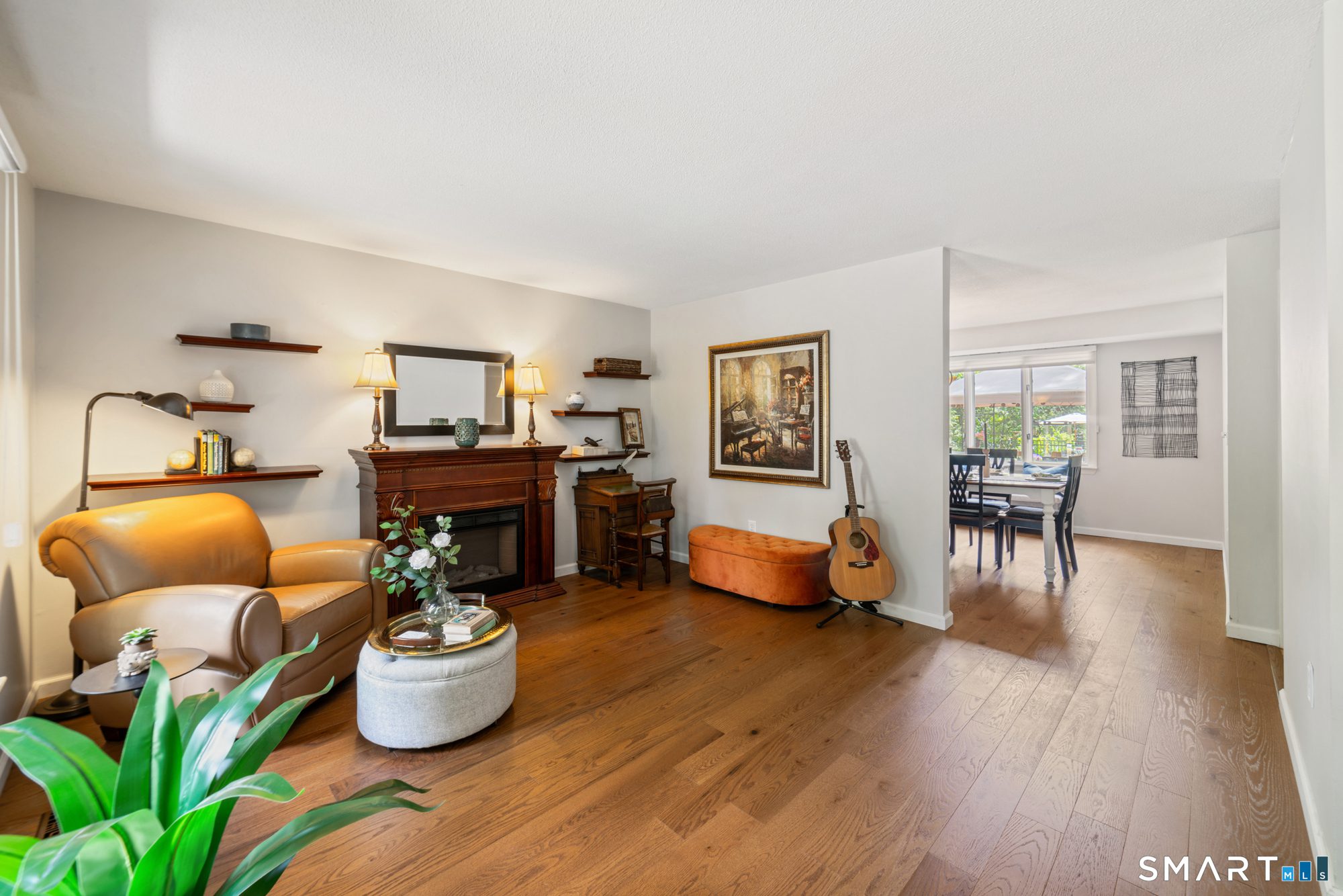 Refined living room space featuring a traditional fireplace, wood floors, and a seamless connection to the dining area.