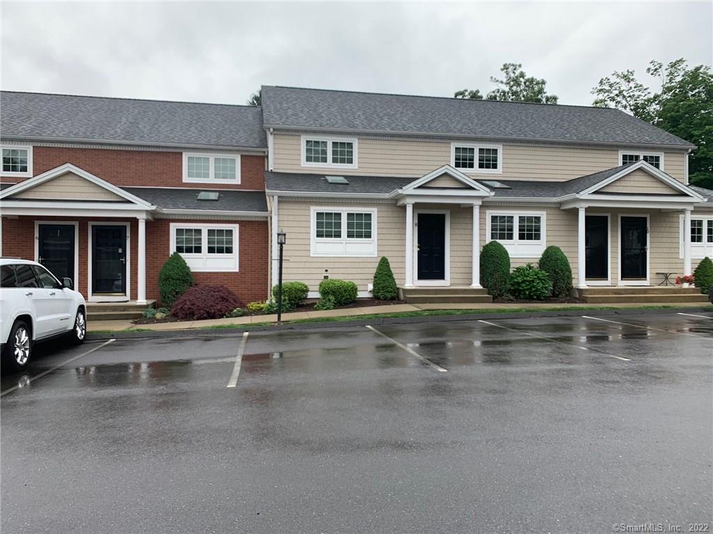 Close-up exterior view of a modern townhouse complex featuring light-colored siding, brick accents, dark-paneled doors, and professional landscaping.