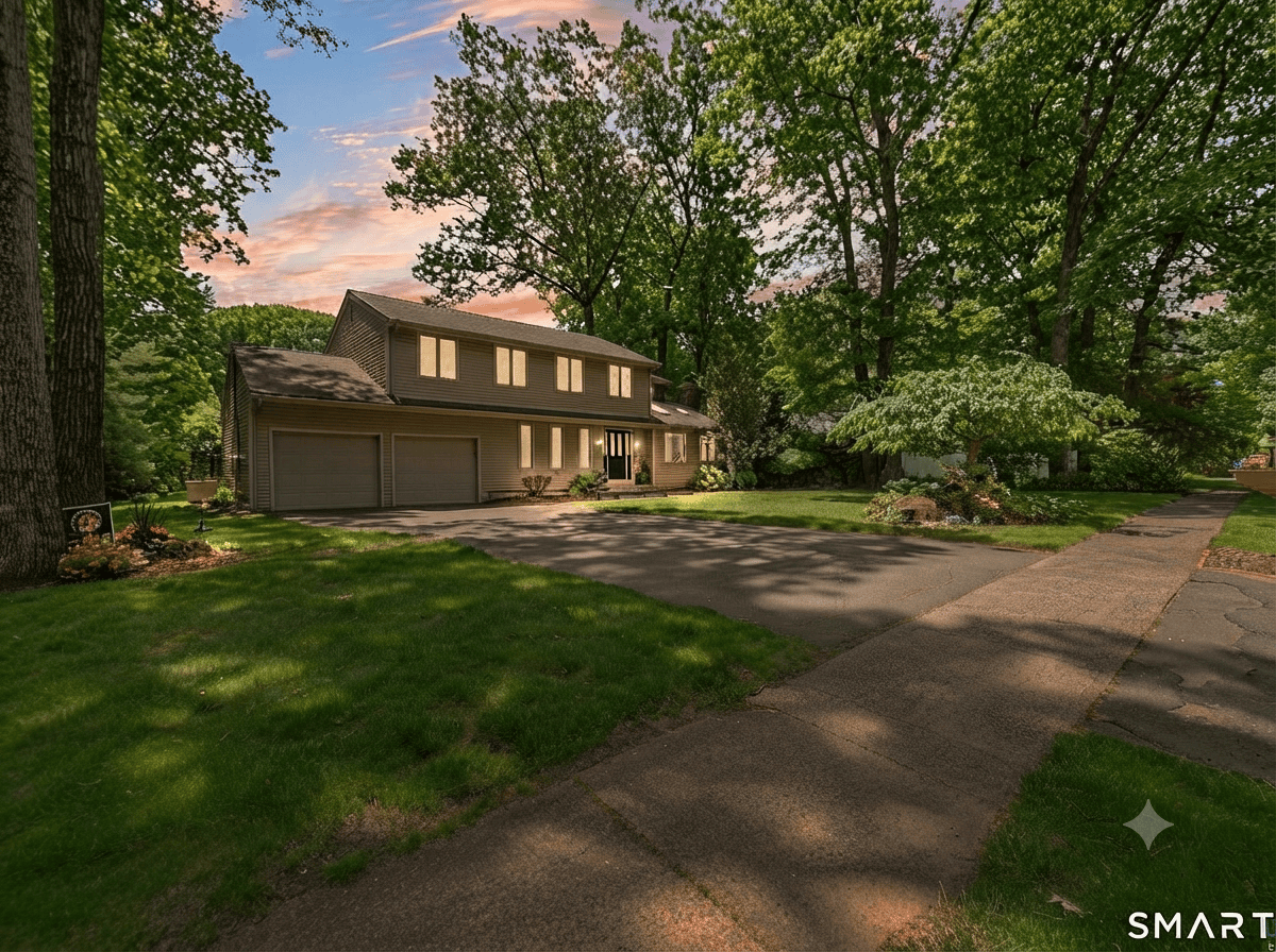 Exterior view of a two-story beige-sided single-family home for sale in Southington, featuring a two-car garage, manicured lawn, and tree-lined street under a twilight sky.