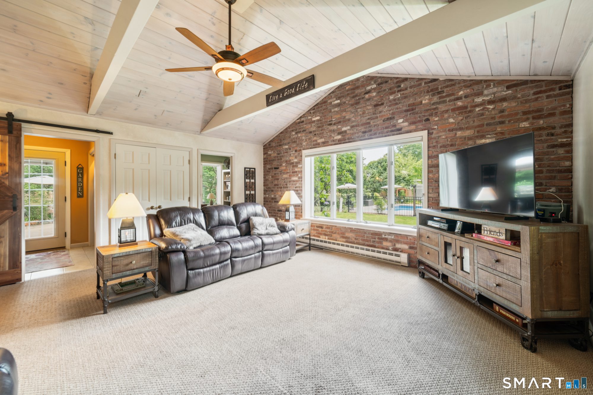 Expansive family room with vaulted ceilings, a stunning floor-to-ceiling brick fireplace, and large windows overlooking the backyard.
