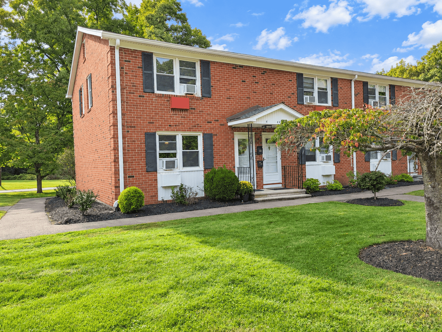 Brick exterior of 488 Radmere Road in the Crestview Condominium complex in Cheshire CT with landscaped lawn and walkway.